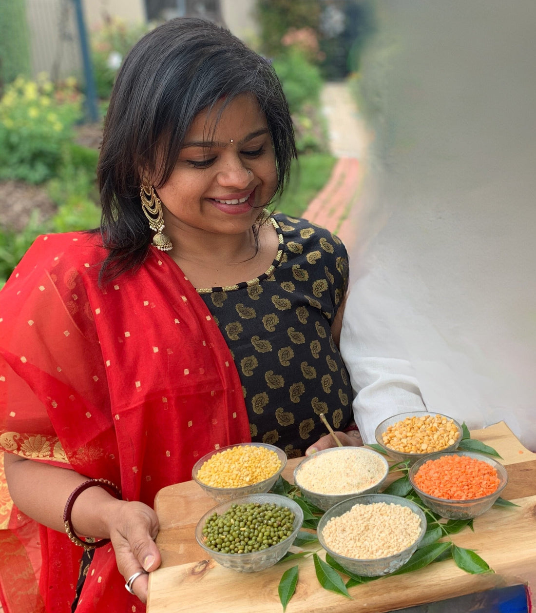 lady holding a tray with different kind of lentils
